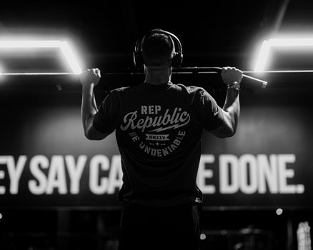 A man exercising with pull-ups in a gym, emphasizing strength and determination with motivational decor.