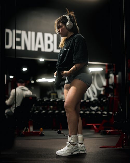 Free Focused young woman exercising with headphones in a modern gym, showcasing determination and fitness motivation. Stock Photo