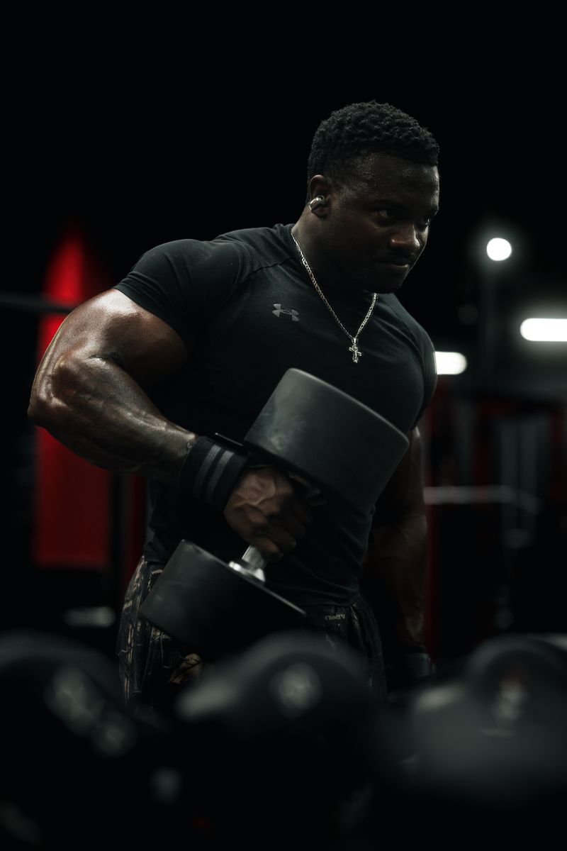 Athlete lifting dumbbells in a dimly lit gym