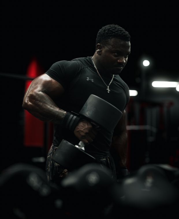 Athlete performing a dumbbell press in a low-lit gym