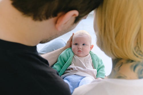 Crop parents communicating with newborn baby in arms