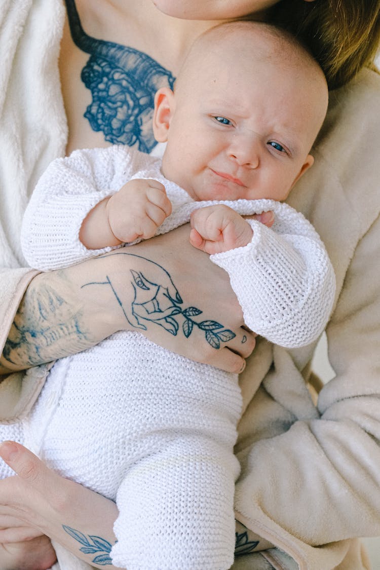 Baby In White Onesie Lying On White Textile