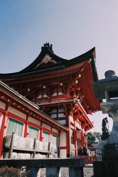 Explore the vibrant red architecture of a traditional Japanese temple with intricate wooden details and blue skies.