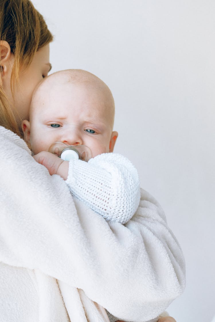 Crop Mom Calming Sleepy Baby With Pacifier In Mouth In Light Studio