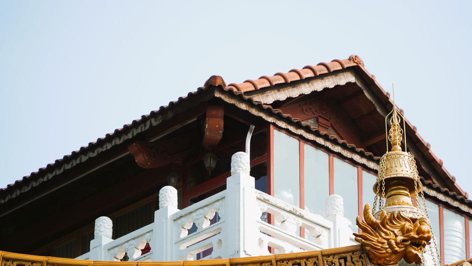 Close-up of a traditional Chinese building roof with intricate decorative elements under clear sky.