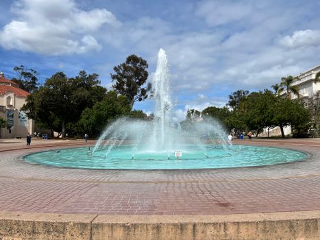 A vibrant fountain in a scenic park with clear blue skies and lush trees, creating a tranquil atmosphere.