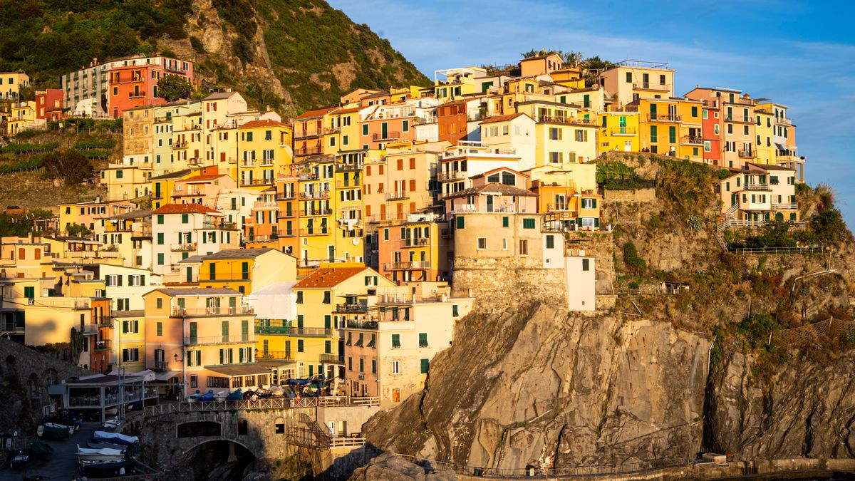 Vibrant pastel buildings of Cinque Terre, Italy, perched on a rugged cliffside at sunset.