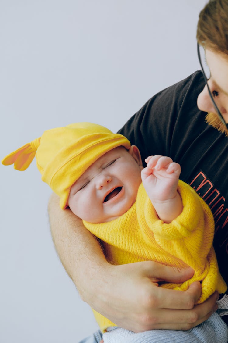 Crop Father In Eyewear Holding Moody Baby In Hands In Studio