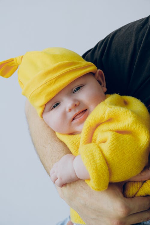 Free Crop father carrying falling asleep baby in arms in light studio Stock Photo