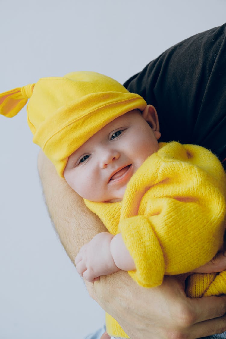 Crop Father Carrying Falling Asleep Baby In Arms In Light Studio