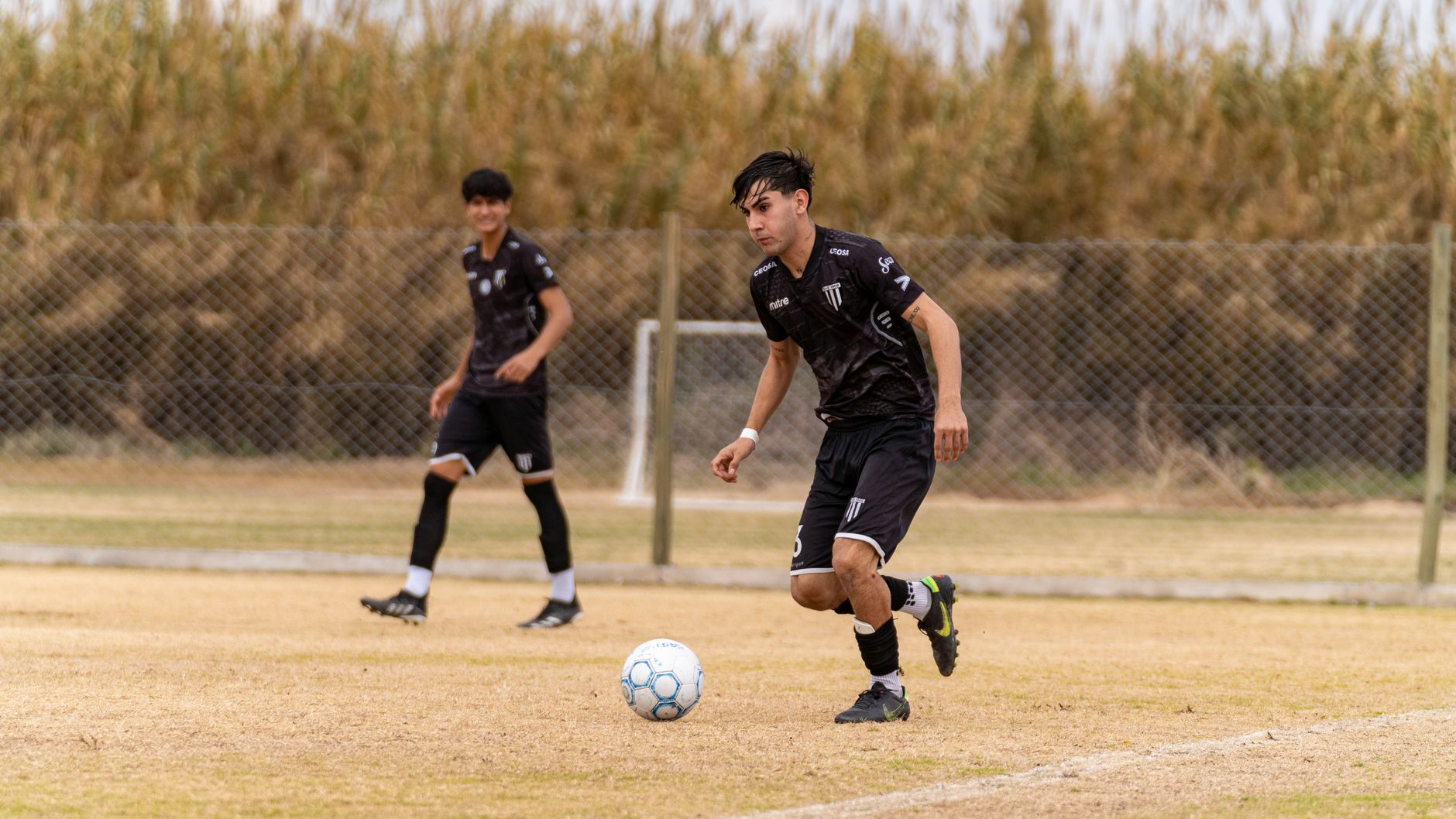 Young football players performing rapid direction changes through scattered training cones