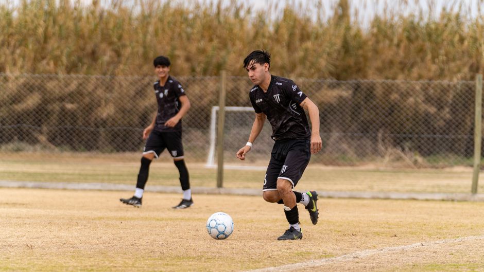 Two young soccer players in black uniforms energetically playing on a field.