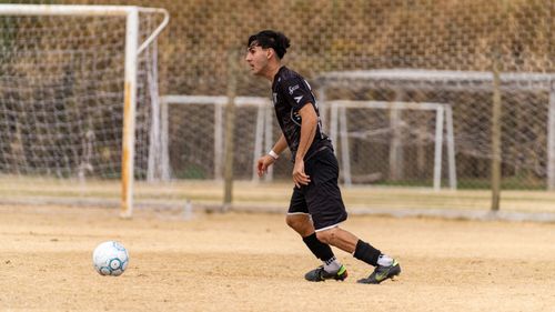 Free Young male soccer player in action on a grass field, focused on the ball during a game. Stock Photo