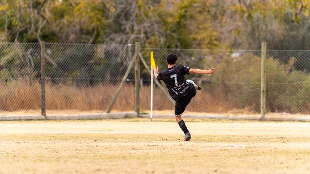 Soccer player skillfully kicks the ball during a match on an outdoor field.
