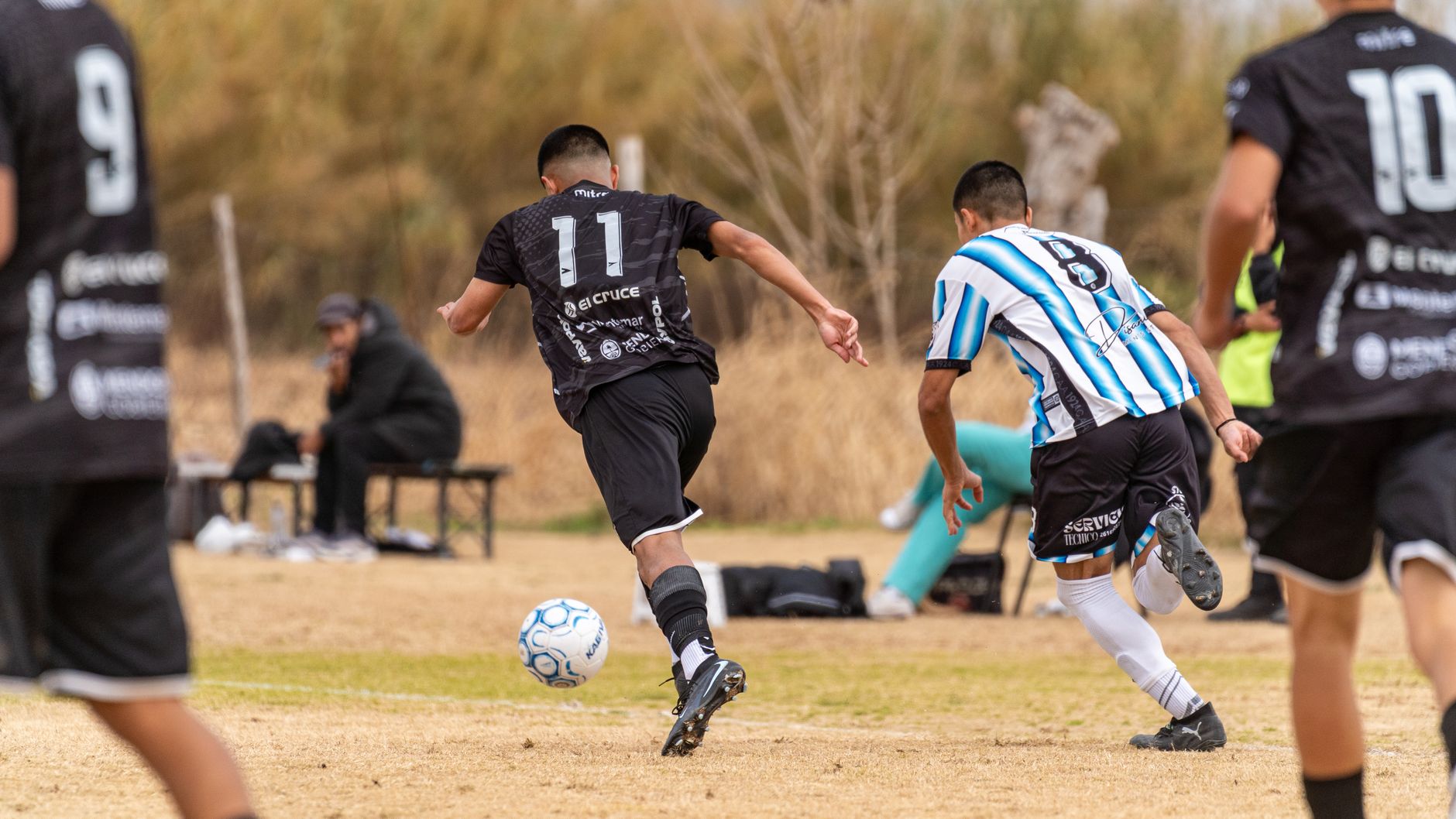 Dynamic scene of an amateur outdoor football match with players in action.