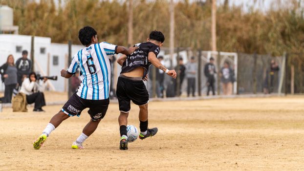Soccer players in an intense match on a dry, dusty field surrounded by spectators., free online jigsaw puzzle on JigsawPuzzlesFreeOnline.org