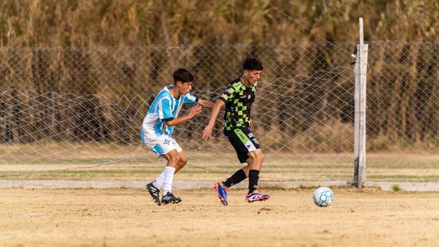 Action-packed soccer game between two teenage players on outdoor field.