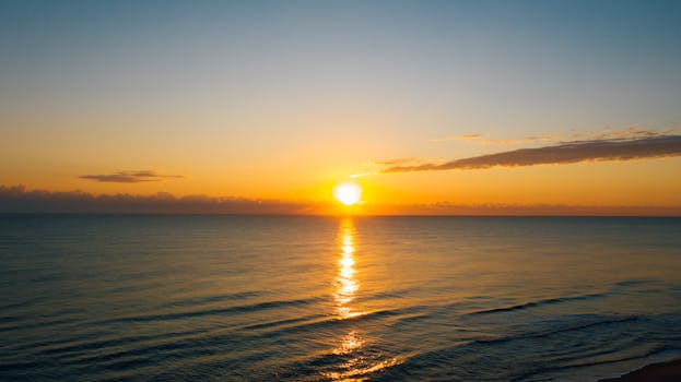 Peaceful sunrise over a calm ocean with golden reflections on the water.