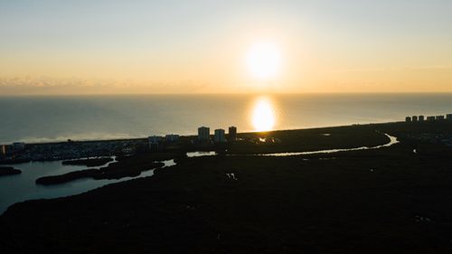 Free Picturesque drone view of coastal terrain near calm sea with reflected sun in water during sundown Stock Photo