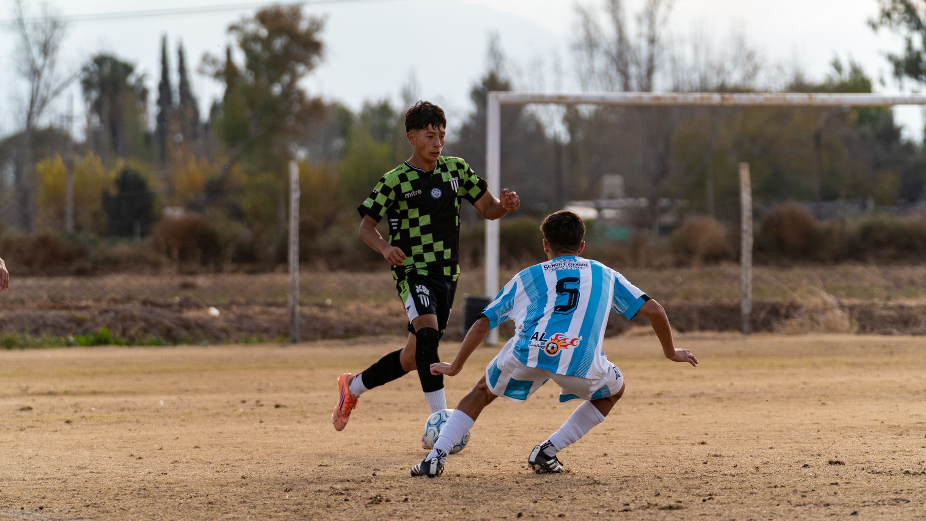 Dynamic moment of two young athletes competing in a soccer match outdoors.