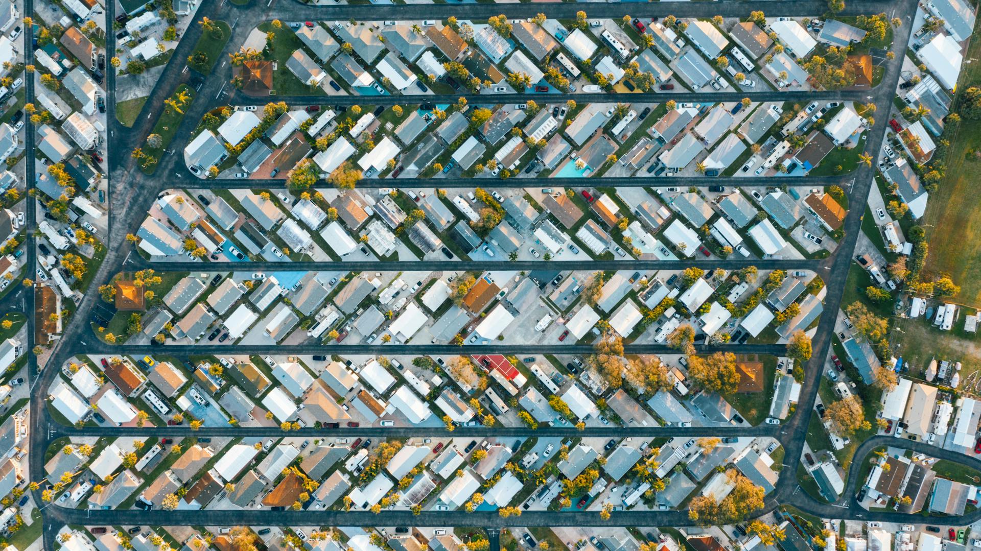 Drone view of modern buildings located in rows between roads in suburb of contemporary town on daytime