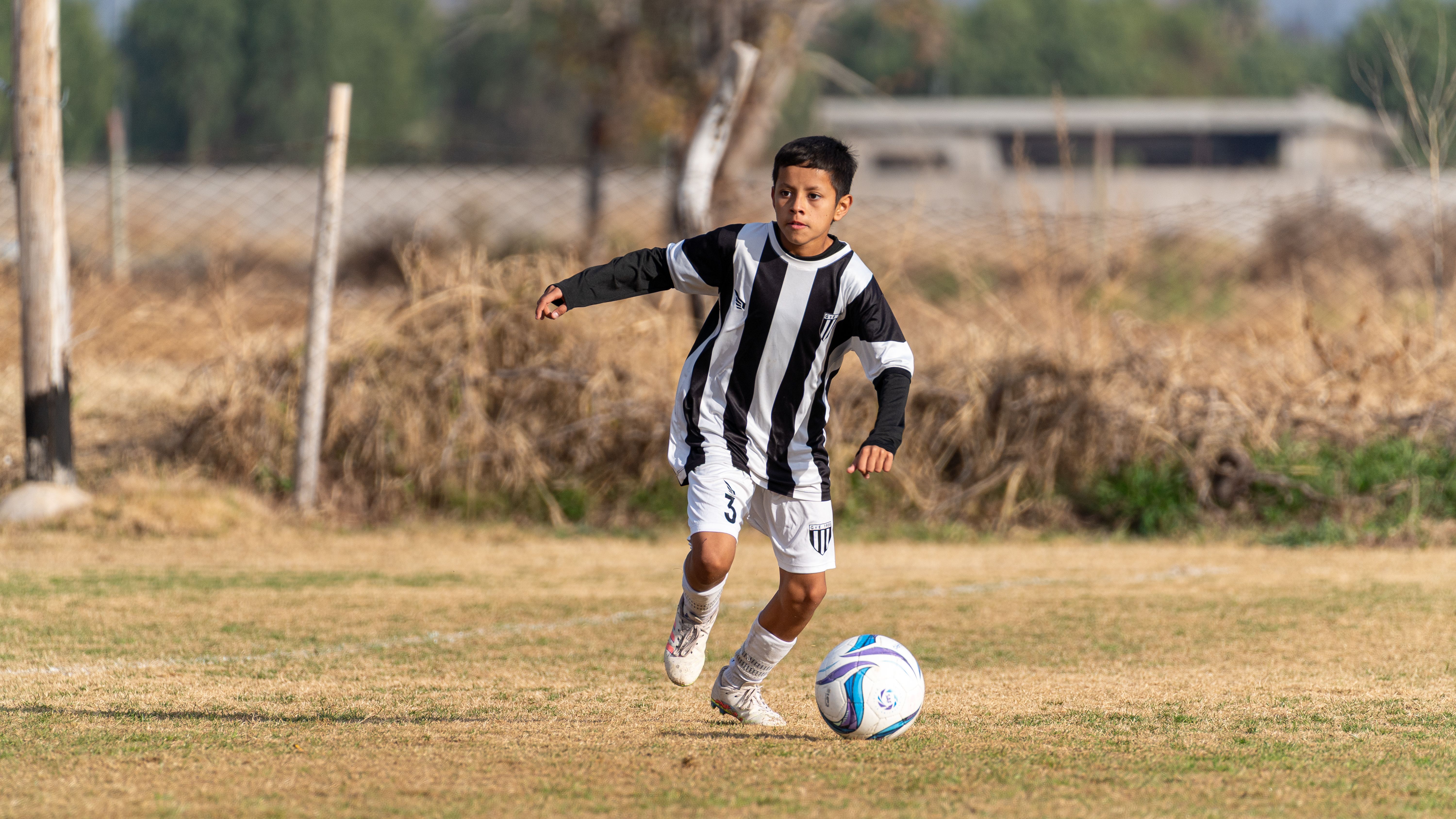 Young soccer player in action on a sunny day, showcasing determination and skill.