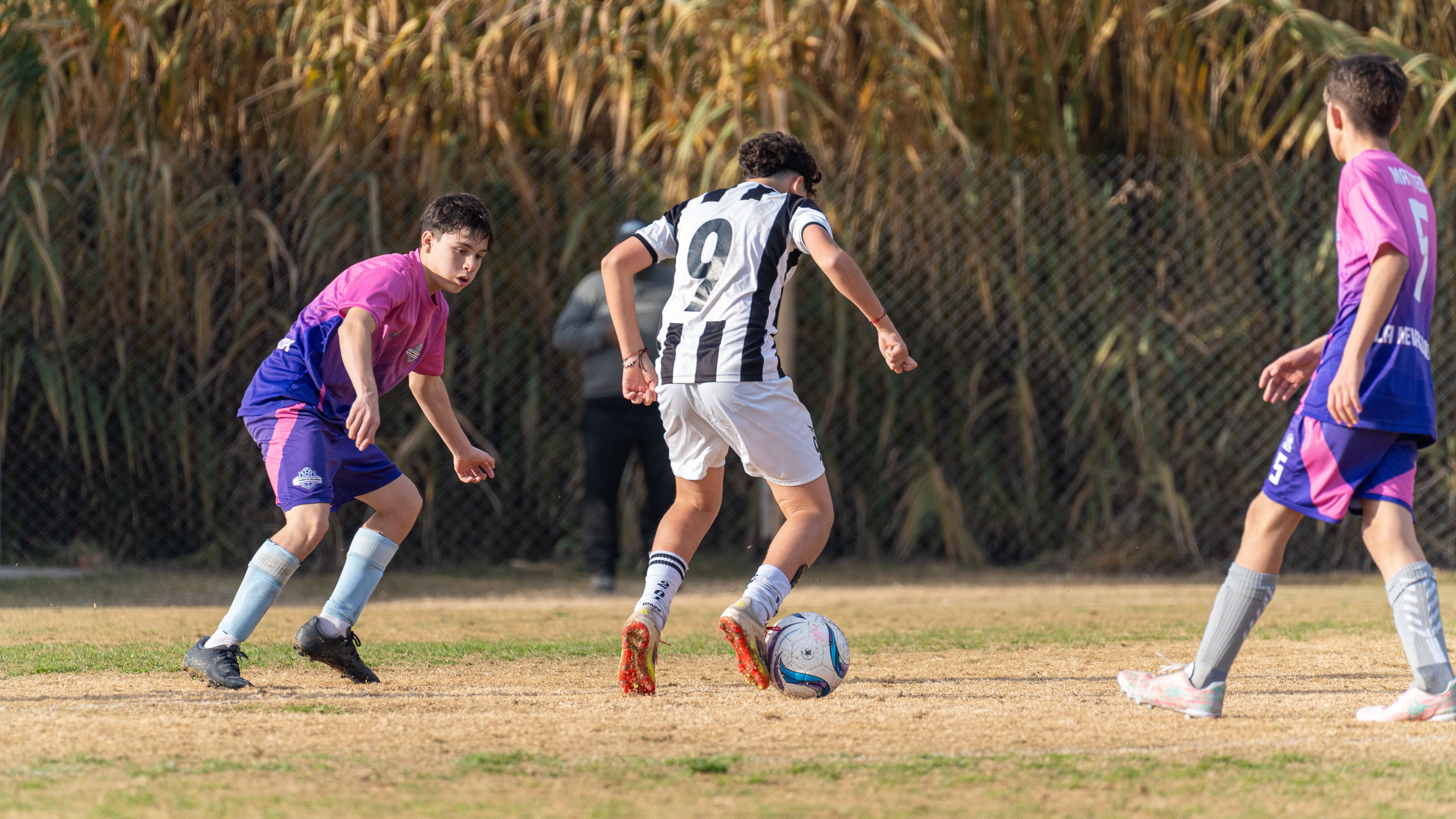 Youth soccer game with players in action outdoors, competing on a grassy field.