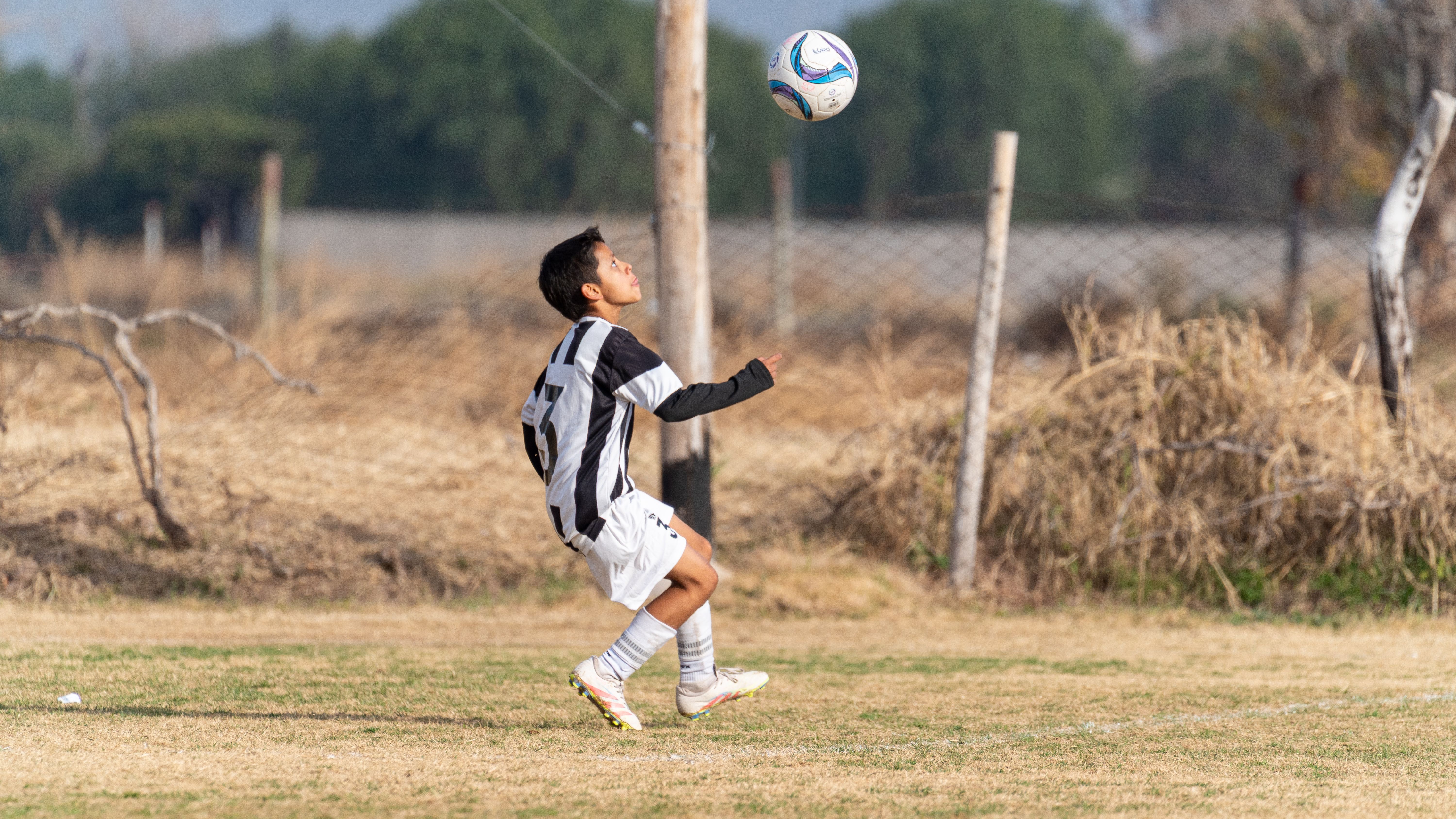 A young soccer player in action performing a header on a grassy outdoor field.