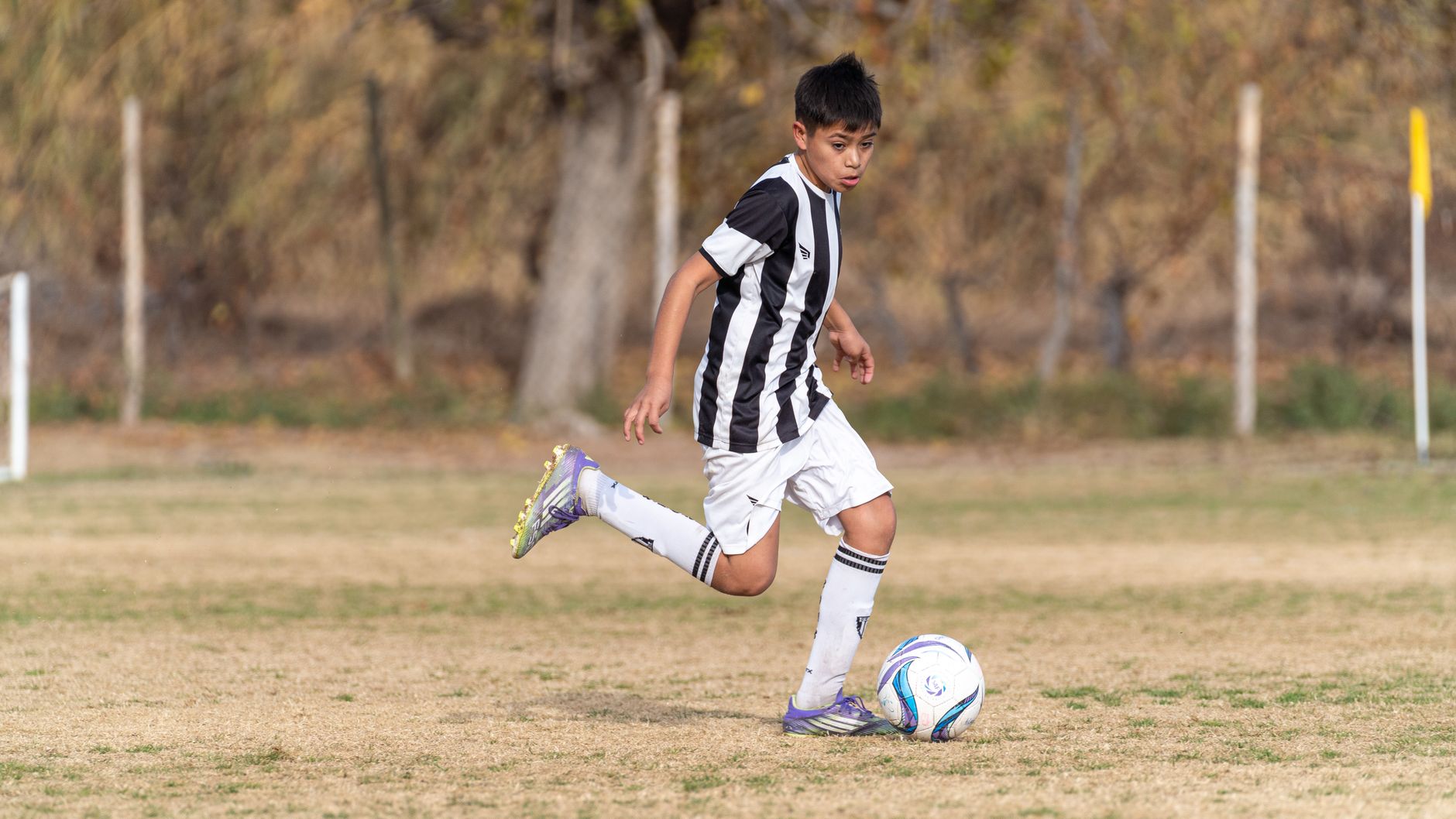 a youth soccer player performing controlled first touches beside cones on a quiet training pitch