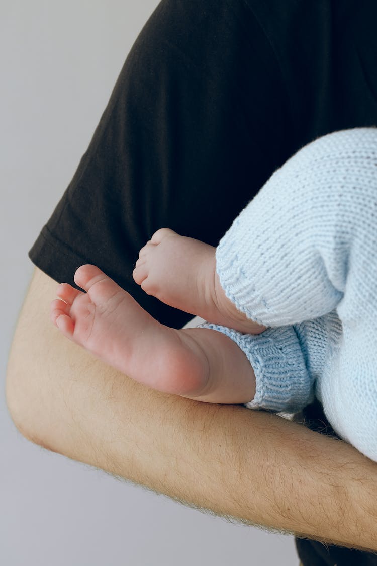 Crop Dad Holding Faceless Infant On Hands Near Gray Wall In Studio