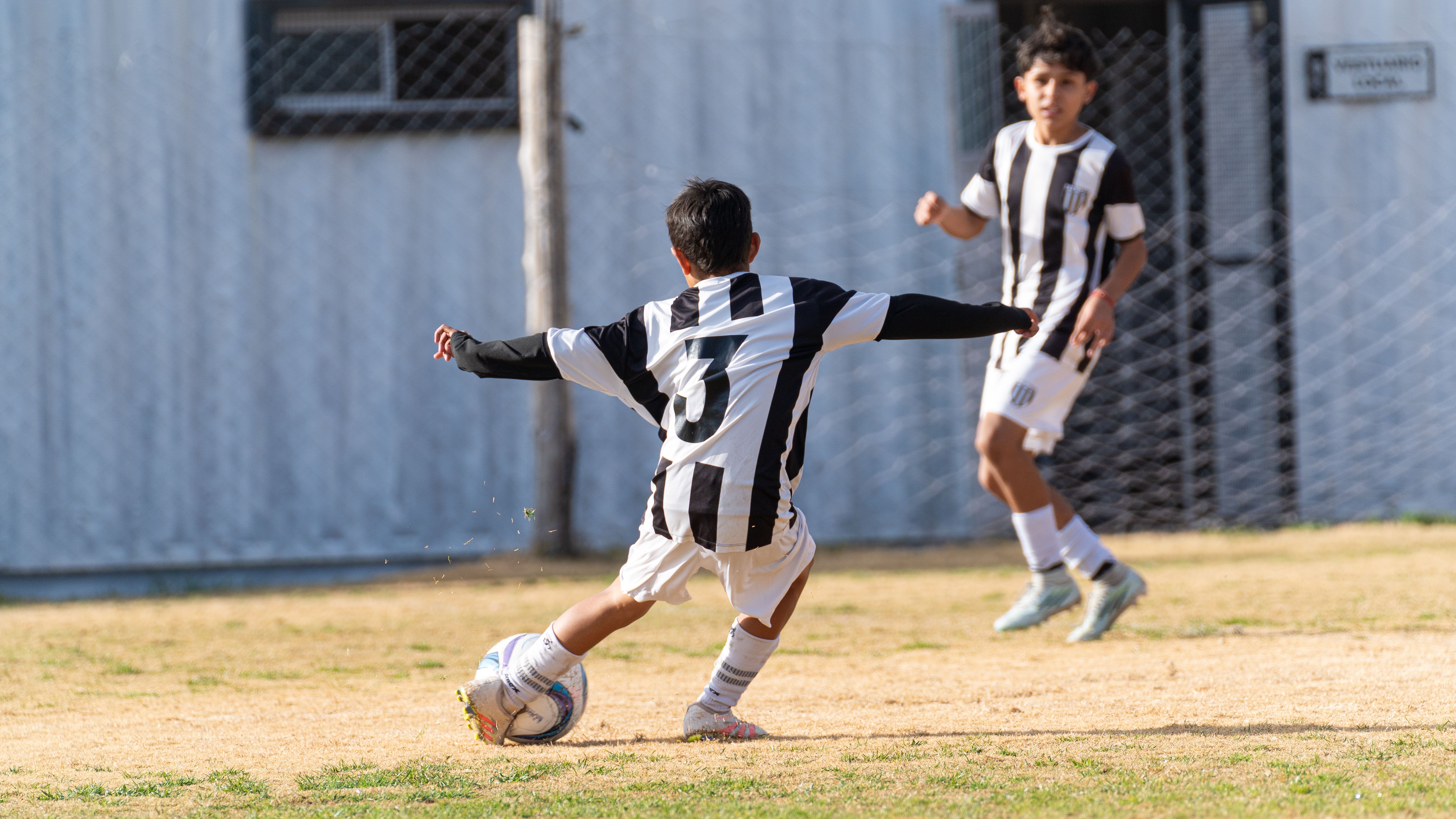 Two young boys playing soccer on a sunny day outdoors.