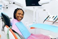 一位女士面带微笑坐在牙科椅上，展现了现代牙科医疗环境