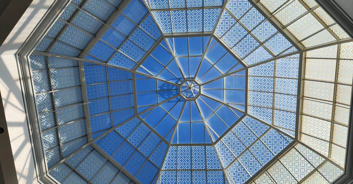 Stunning geometric dome ceiling with intricate glass panels and blue sky view.