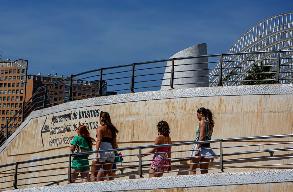Turistas paseando junto a edificios de arquitectura moderna en Valencia, España, bajo un cielo azul despejado.