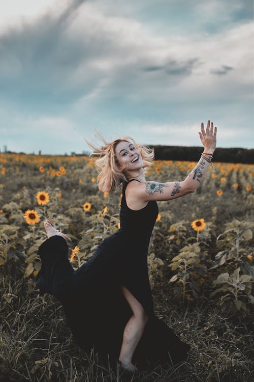 Woman in Black Dress Standing on Sunflower Field