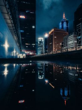 Moody nighttime cityscape of Hong Kong with stunning building reflections.