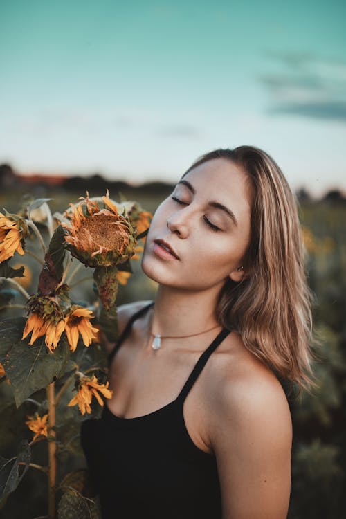 Free Woman in Black Spaghetti Strap Top Holding Sunflower Stock Photo