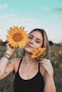 一位女子在田野里手持向日葵，微笑着展现美丽与自然
