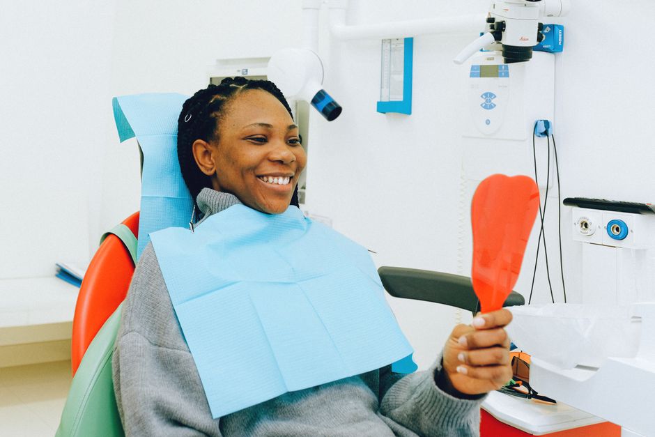 A patient checking her smile with a mirror after a visit
