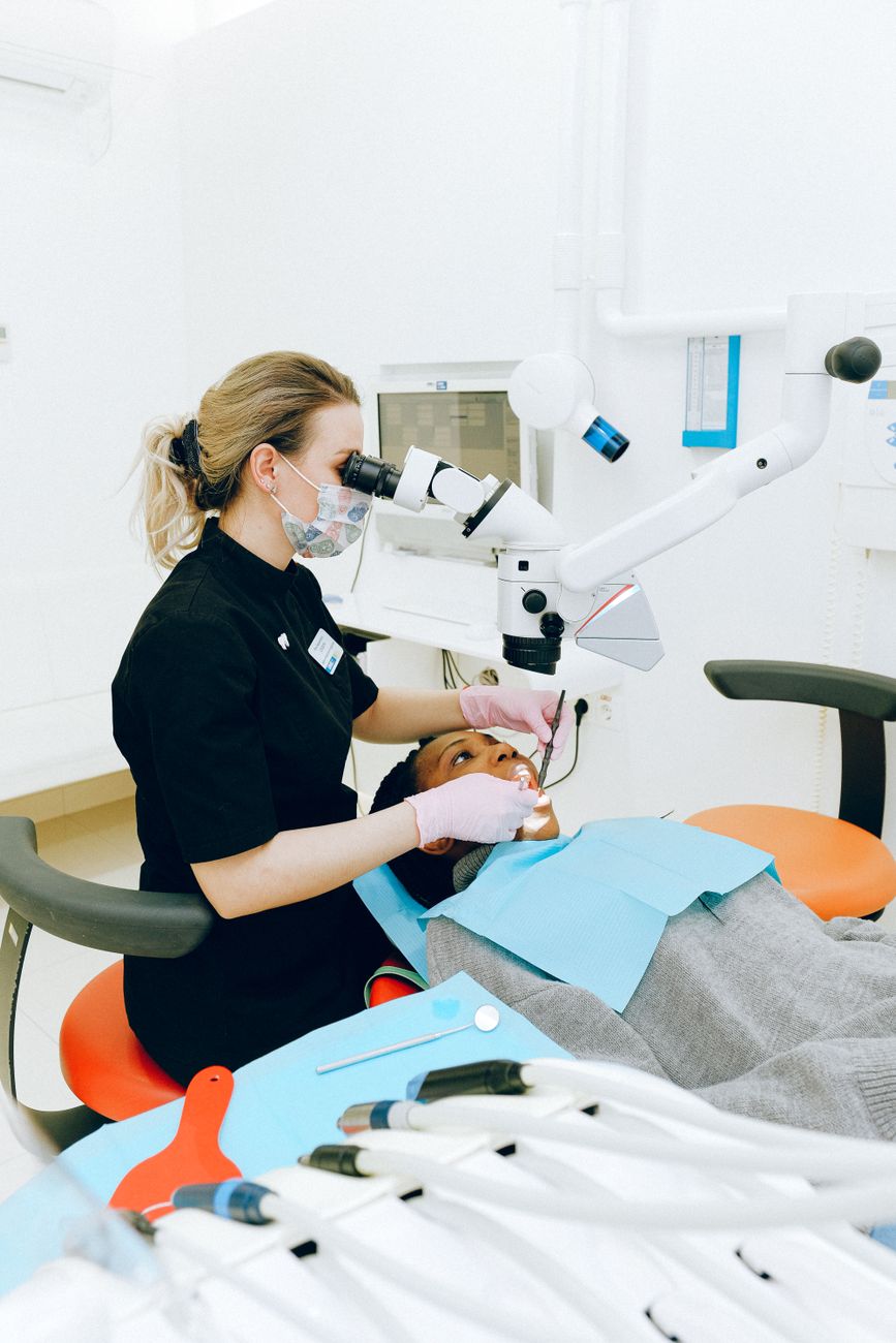 A dental hygienist gently performing a professional cleaning on a patient in a bright dental office, representing periodontal care at The Village Dentist in Bloor West Village