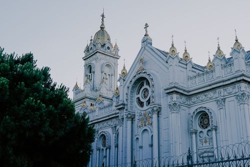Free A beautiful white church with intricate details and gold accents, captured from a side angle with a serene backdrop. Stock Photo