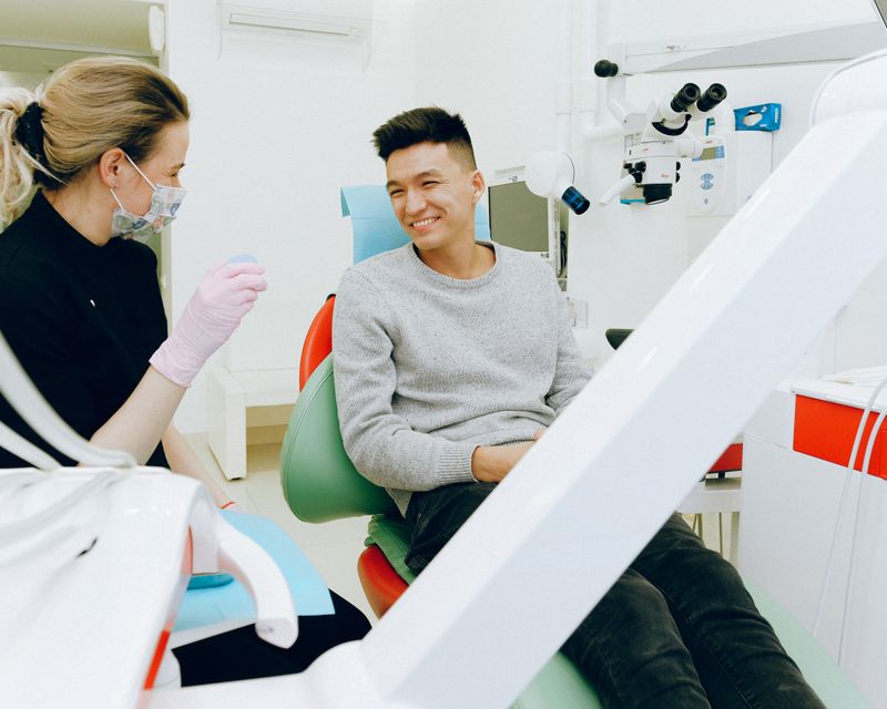 A teenager relaxing in a dental chair while talking with the dentist