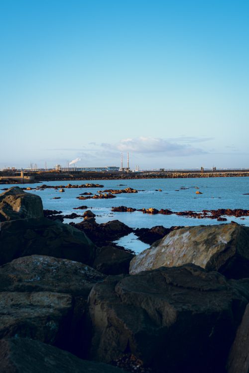 Free Scenic view of rocky coastline with iconic towers of Dublin in background during day. Stock Photo