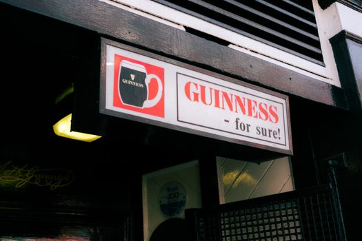 A vintage Guinness sign outside a pub with classic wooden decor.