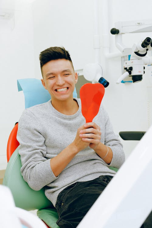 Smiling Man in Gray Sweater Holding Orange Mirror