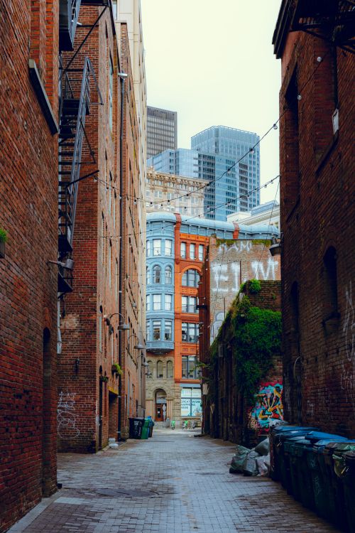 Free Explore a historic Seattle alleyway nestled between brick buildings with a modern city skyline backdrop. Stock Photo