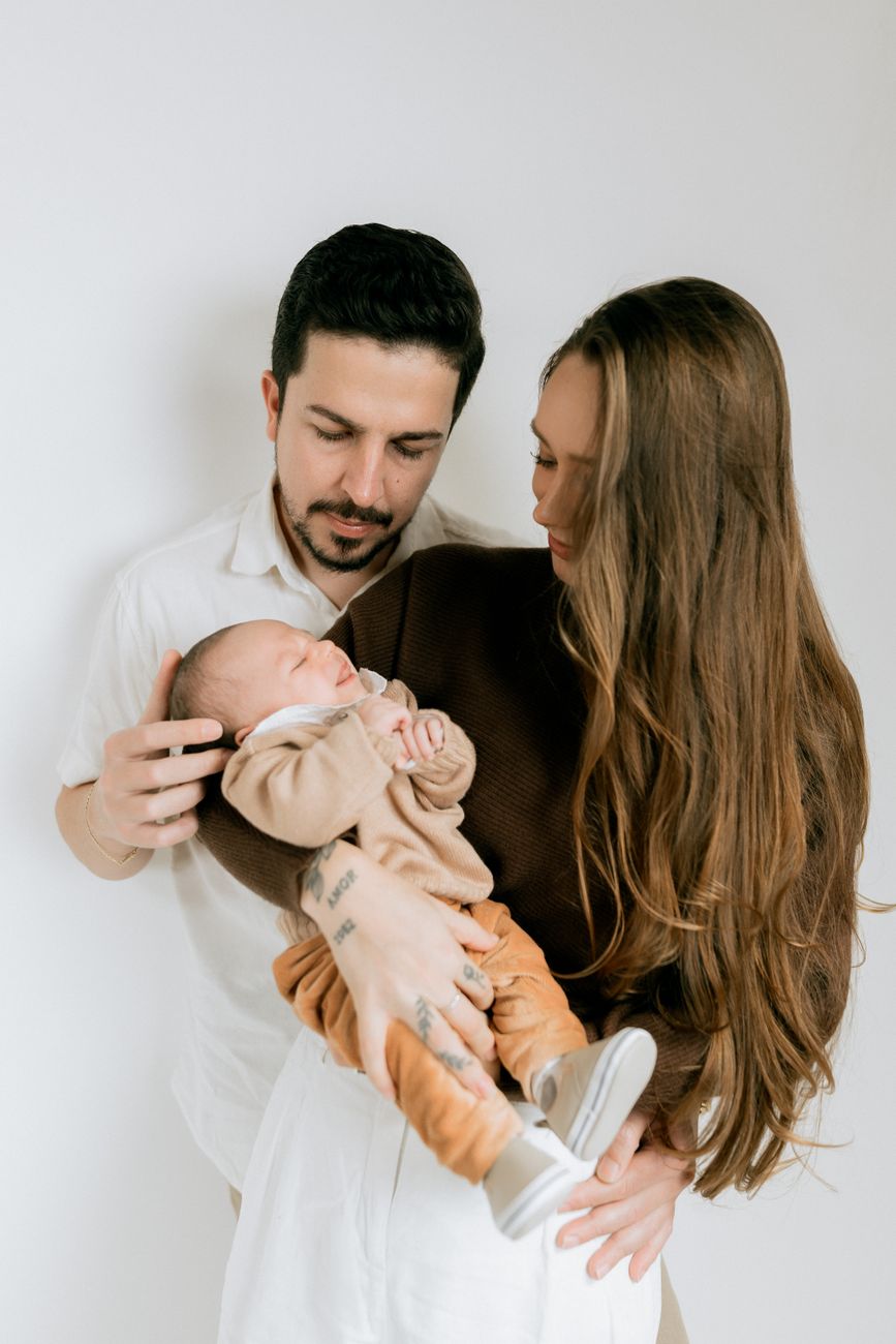 Pais segurando ternamente o bebê recém-nascido dormindo