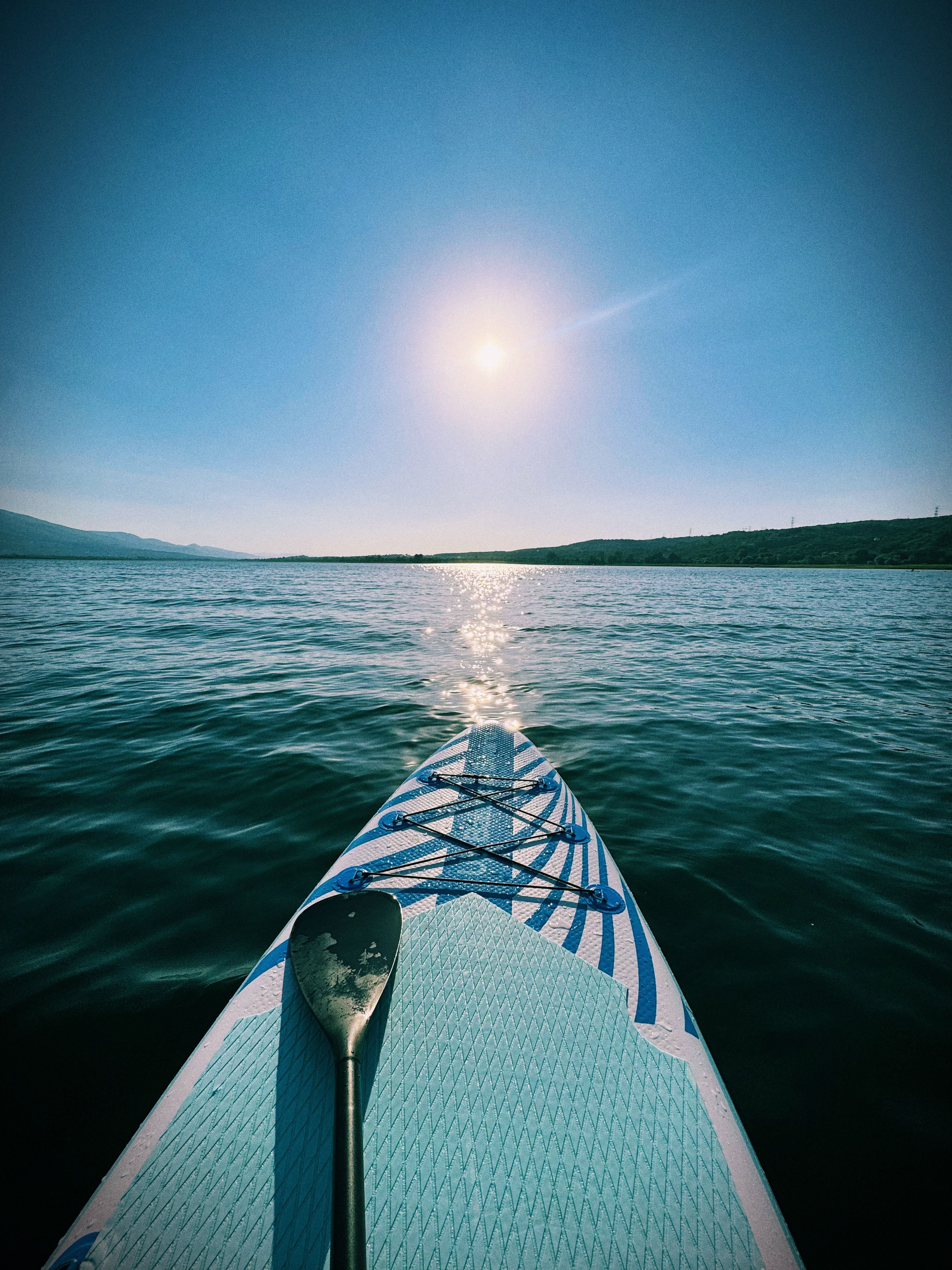 Paddle board and paddle on a calm lake at sunrise