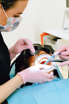 Dentist examining patient's teeth with dental tools and face mask in clinic setting.