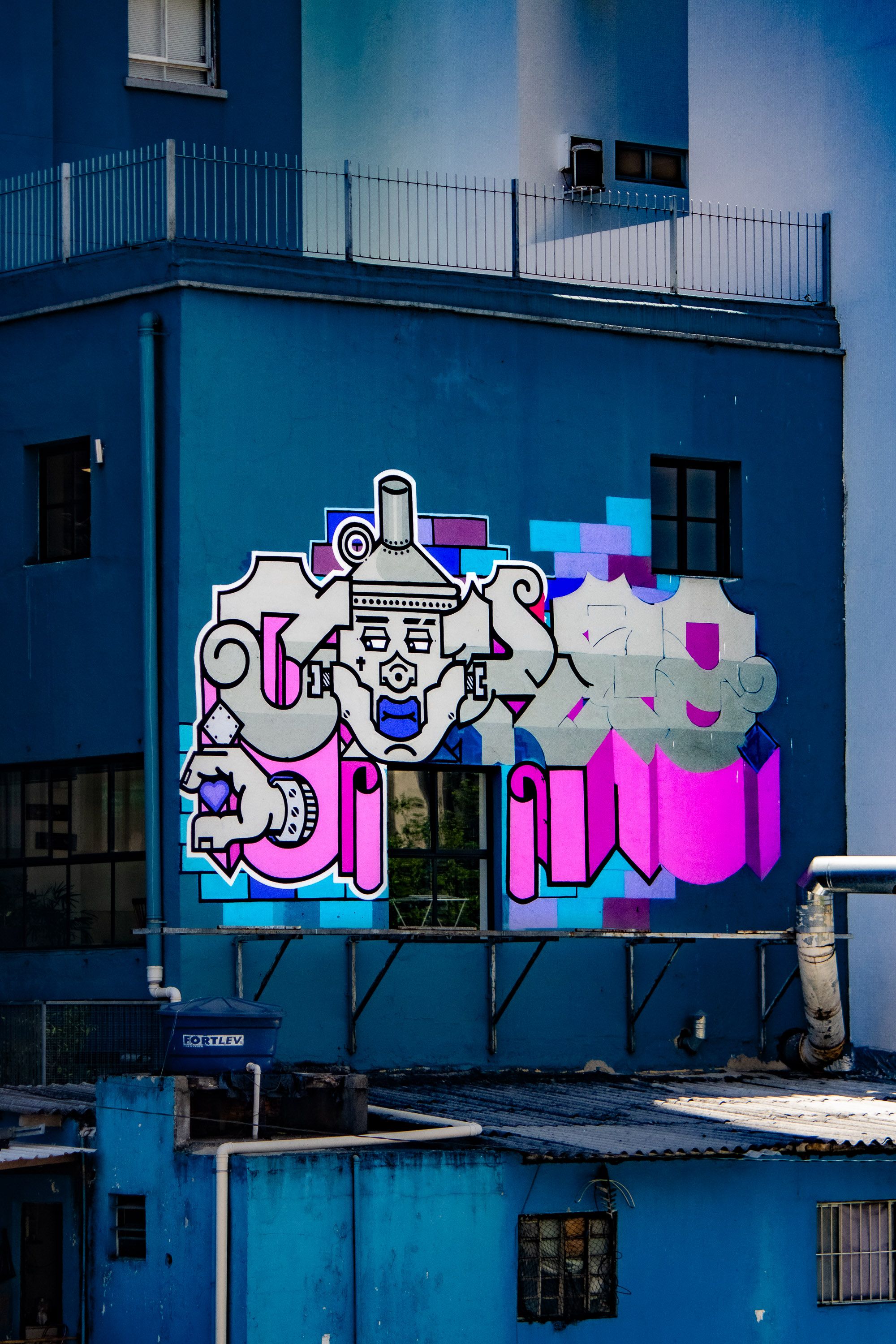 Colorful graffiti art adorns a blue building's wall in an urban setting, showcasing street culture.